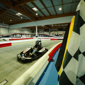 un kart sur la piste couverte à vitesse k1 le mans avec un drapeau à damier au premier plan